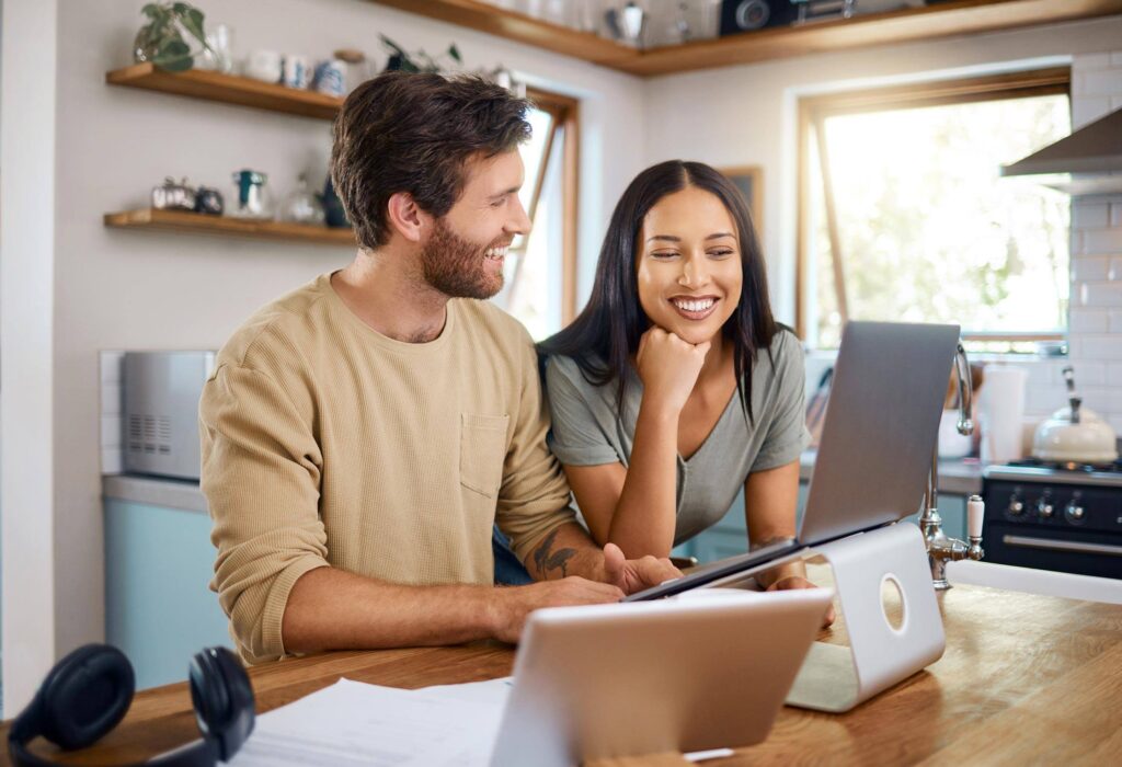 Couple smiling while looking at laptop