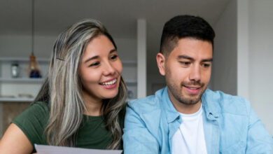 Couple smiling while looking at utility bill and laptop