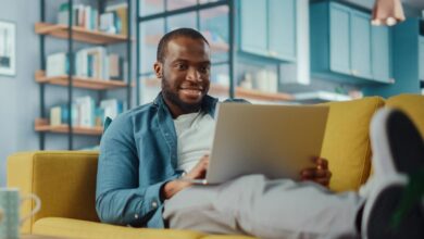 Man smiling while sitting on the couch looking at his laptop