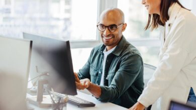 Man working on computer with coworker standing next to him