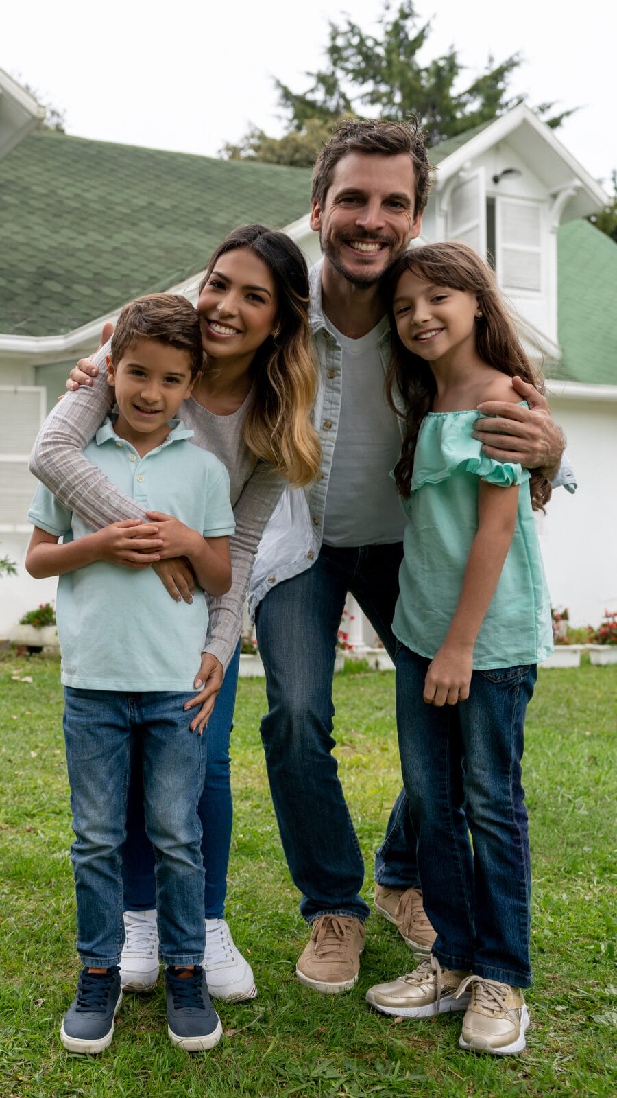 Dad, mom, daughter and son standing outside of home posing for a picture