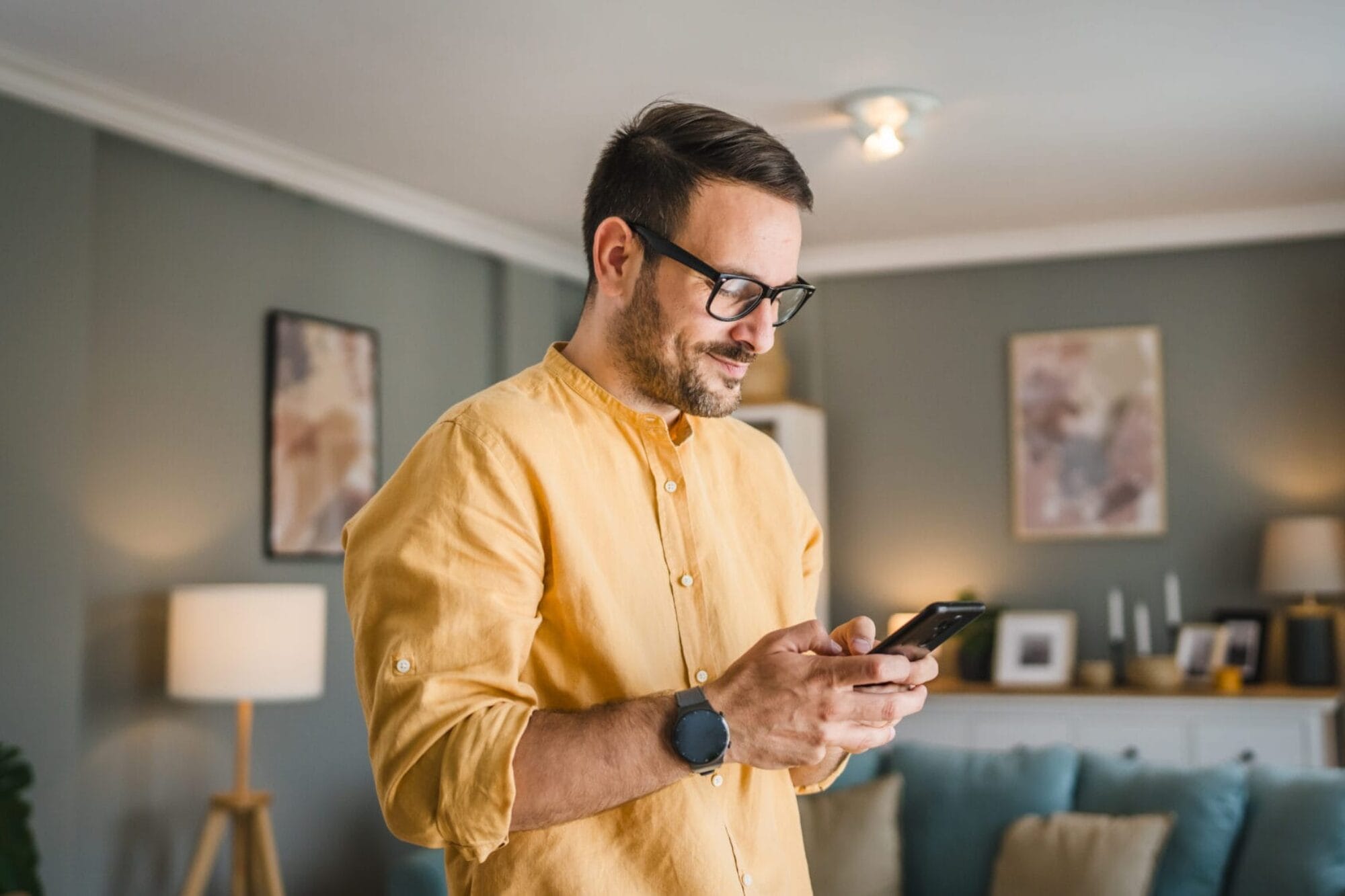 One adult man with eyeglasses stand at home use mobile phone