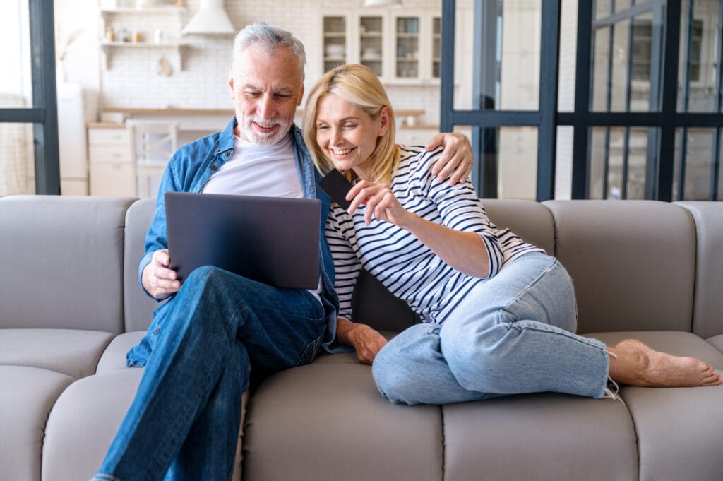 Happy mature family couple with laptop and credit card shopping online